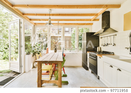 Home interior design of modern loft apartment with open kitchen in minimalist style and spacious dining zone with table and chairs 97711958