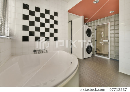 Tiled shower cabin with glass door located near sink and mirror in light restroom in contemporary apartment 97712287