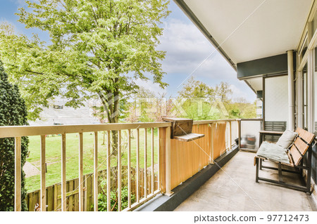 Narrow wooden balcony with wooden railings, wooden chair and door Narrow wooden balcony with wooden railings, wooden chair and door 97712473