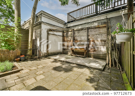 Neat paved patio with sitting area and small garden near wooden fence 97712673
