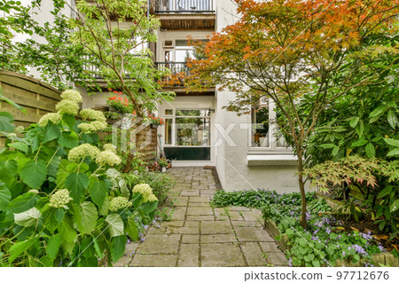Neat paved patio with sitting area and small garden near wooden fence Neat paved patio with sitting area and small garden near wooden fence 97712676