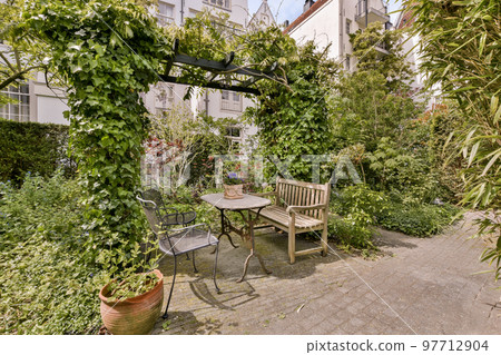 Neat paved patio with sitting area and small garden near wooden fence Neat paved patio with sitting area and small garden near wooden fence 97712904