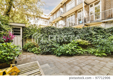 Neat paved patio with sitting area and small garden near wooden fence 97712906