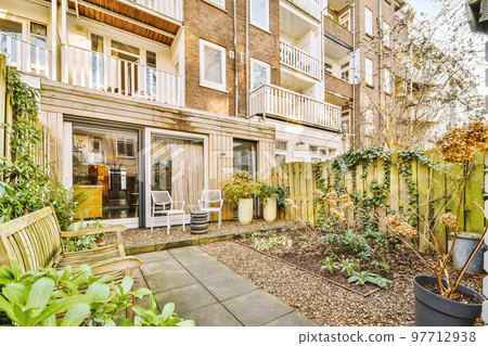 Neat paved patio with sitting area and small garden near wooden fence 97712938