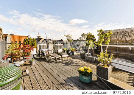 Bright wooden balcony with metal railings, wooden chair and door 97713016