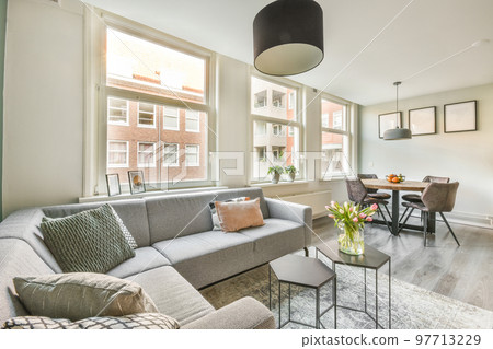Table with chairs and flowers located near lounge area and kitchen in spacious room of contemporary apartment Table with chairs and flowers located near lounge area and kitchen in spacious room of contemporary apartment 97713229