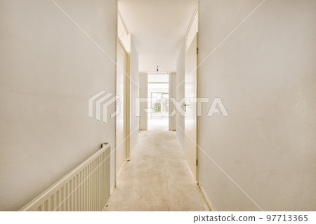 Light narrow hallway with many doors in white walls and glowing lamp over lumber floor 97713365