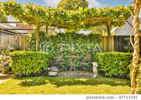Neat paved patio with sitting area and small garden near wooden fence 97713385