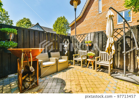 Neat paved patio with sitting area and small garden near wooden fence 97713457