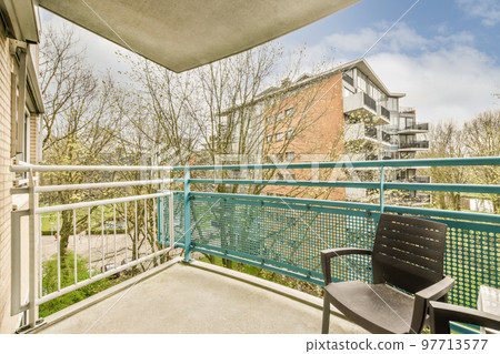 Narrow brick balcony with metal railings, wooden chair and door with glass leads to the kitchen 97713577