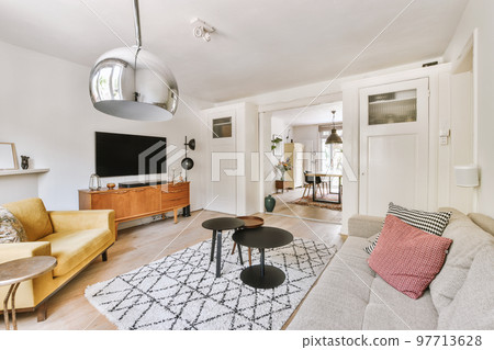 Interior of living room with comfortable sofa and TV against windows in contemporary apartment 97713628