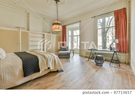 Comfortable bed with colorful pillows and warm blanket located near window in stylish bedroom with green walls Comfortable bed with colorful pillows and warm blanket located near window in stylish bedroom with green walls 97713657