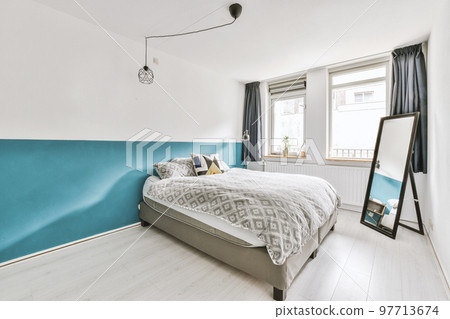 Modern home interior design of small mansard bedroom with white walls and soft cozy bed and minimalist style shelves in daylight with illumination 97713674