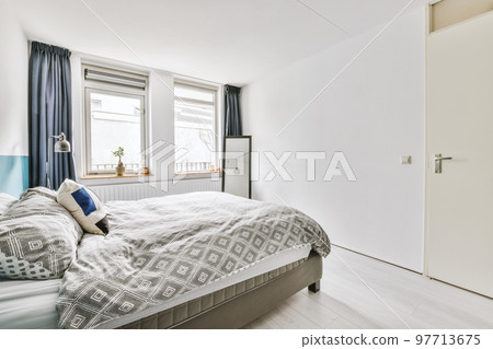 Modern home interior design of small mansard bedroom with white walls and soft cozy bed and minimalist style shelves in daylight with illumination 97713675