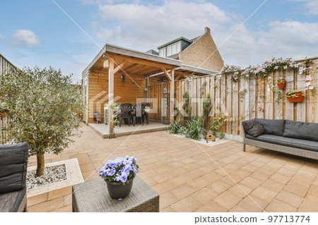 Neat paved patio with sitting area and small garden near wooden fence 97713774