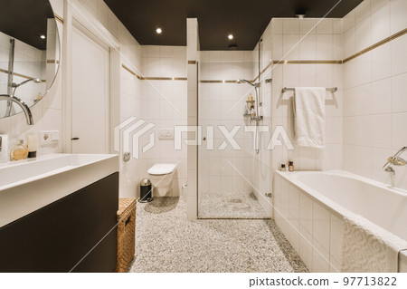 Sinks with mirrors and clean bathtub located near shower box with glass door in modern bathroom with white tiled walls Sinks with mirrors and clean bathtub located near shower box with glass door in modern bathroom with white tiled walls 97713822