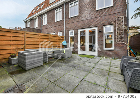 Neat paved patio with sitting area and small garden near wooden fence Neat paved patio with sitting area and small garden near wooden fence 97714002