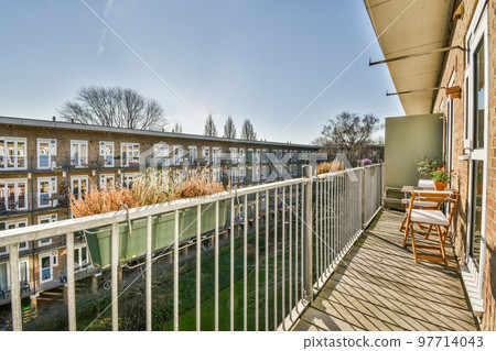 Front view of buildings and cars with bicycles from small balcony with railings 97714043