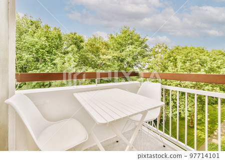 Narrow brick balcony with metal railings, wooden chair and door Narrow brick balcony with metal railings, wooden chair and door 97714101