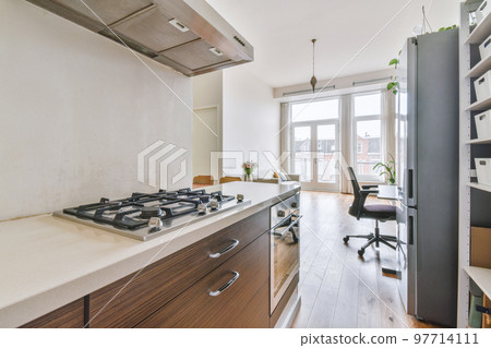 Fragment of interior of light narrow home kitchen with minimalist style white furniture with sink and stove Fragment of interior of light narrow home kitchen with minimalist style white furniture with sink and stove 97714111