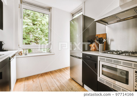 Fragment of interior of light narrow home kitchen with minimalist style white furniture with sink and stove Fragment of interior of light narrow home kitchen with minimalist style white furniture with sink and stove 97714166