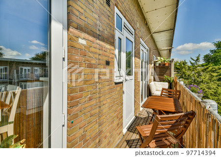 Narrow brick balcony with metal railings, wooden chair and door Narrow brick balcony with metal railings, wooden chair and door 97714394