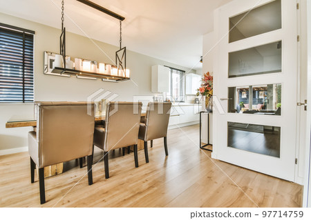 a dining room with wood flooring and white trim on the walls, along an open door that leads to a kitchen a dining room with wood flooring and white trim on the walls, along an open door that leads to a kitchen 97714759