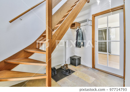 a wooden staircase in a room with white walls and wood steps leading up to the second floor there is a mirror on the wall 97714793