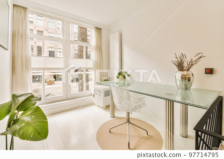 a room with a desk, chair and large window looking out onto the street in front of the apartment building 97714795