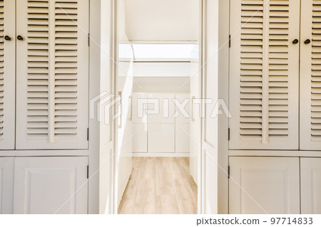 the inside of a house with shutters on the doors and wood flooring in the hallway leading to another room 97714833