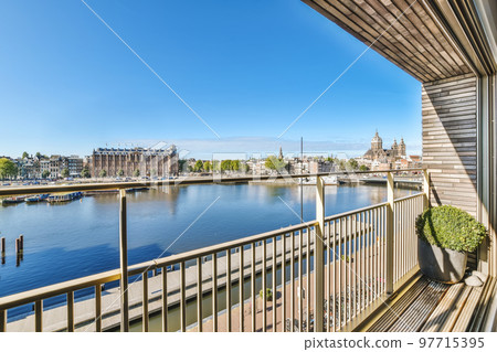 a balcony with a view of the water and buildings in the distance, taken from an apartment window looking out onto the canal 97715395