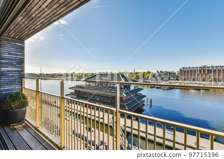 a boat going down the river on a sunny day with blue sky and white clouds in the photo is taken from a balcony 97715396