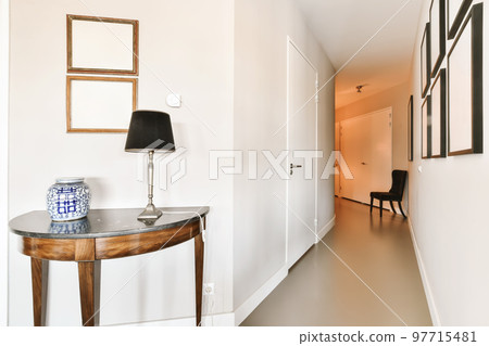 a hallway in an apartment with white walls and wood flooring on the right side of the room is a small console table a hallway in an apartment with white walls and wood flooring on the right side of the room is a small console table 97715481