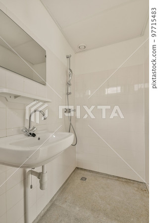 Interior of narrow restroom with sink and flush toilet 97715483