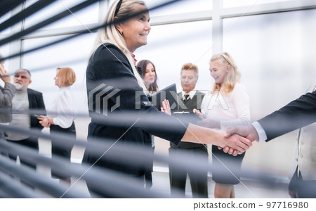 through-blinds. business colleagues meeting each other with a handshake. through-blinds. business colleagues meeting each other with a handshake. 97716980