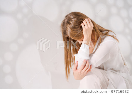 Thoughtful woman on background with light art shadows , sad mood Thoughtful woman on background with light art shadows , sad mood 97716982