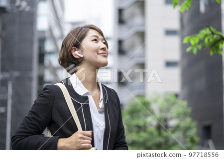 Business woman in her thirties wearing wireless earphones Business woman in her thirties wearing wireless earphones 97718556