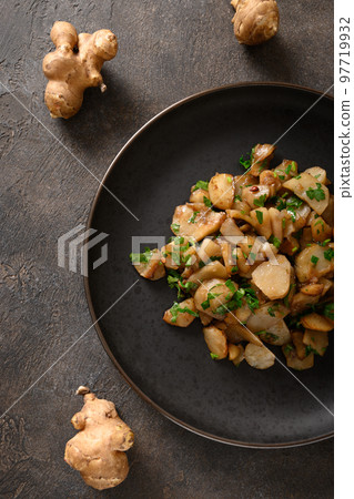 Roasted Jerusalem artichoke root, sunchokes on dark brown. 97719932