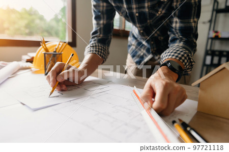 business man hand working and laptop with on on architectural project at construction site at desk in office. 97721118