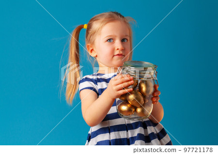 Little cute girl holding glass jar with golden eggs colored for Easter Little cute girl holding glass jar with golden eggs colored for Easter 97721178
