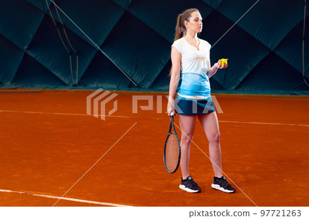 Young woman playing tennis at indoor tennis court 97721263