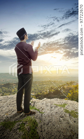 Muslim man standing while raised hands 97722670
