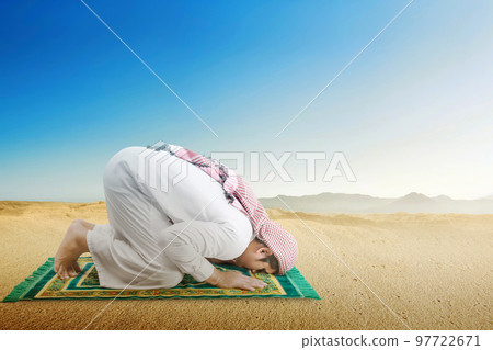 Muslim man with keffiyeh and agal in praying position (salat) on the prayer rug 97722671