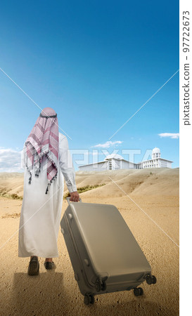 Rear view of an Arab man wearing keffiyeh and agal walking with a suitcase for traveling in the desert Rear view of an Arab man wearing keffiyeh and agal walking with a suitcase for traveling in the desert 97722673