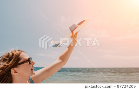 Woman hand holding toy airplane on blue sky and white clouds at sunset sea beach abstract background. Travel adventure and freedom concept. Woman hand holding toy airplane on blue sky and white clouds at sunset sea beach abstract background. Travel adventure and freedom concept. 97724209