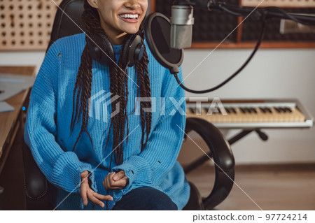 Anchorwoman with beautiful toothy smile talking into microphone in the broadcasting and music recording studio 97724214