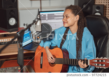Charming talented teenage African girl guitarist recording new song in the broadcasting and sound recording music studio 97724215
