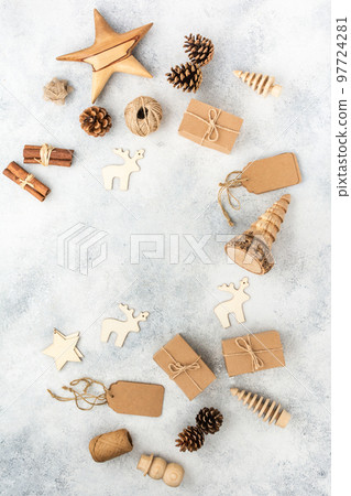 Christmas background, presents in brown boxes, pine cones, scissors, wooden ornament on white wooden table 97724281