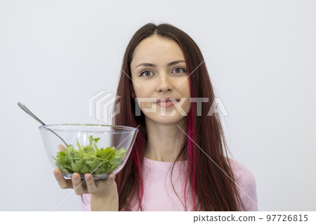 Young woman with an eating disorder eats lettuce leaves. Slim girl on a diet. Young woman with an eating disorder eats lettuce leaves. Slim girl on a diet. 97726815