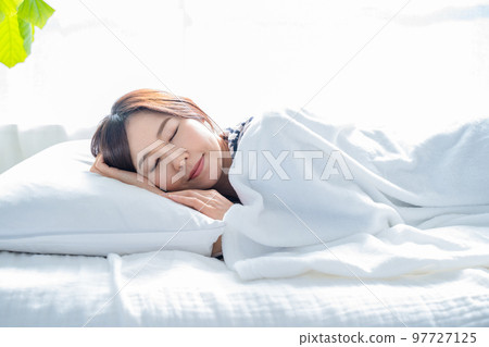 在一間明亮的簡單房間裡睡在床上的女人 97727125